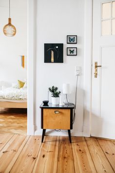 a small wooden table sitting on top of a hard wood floor next to a white door