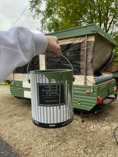 a person holding a paint can in front of a camper