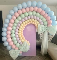 a large balloon arch with pastel colors and bows