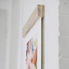 a photo hanging on the wall next to a white brick wall with a wooden frame