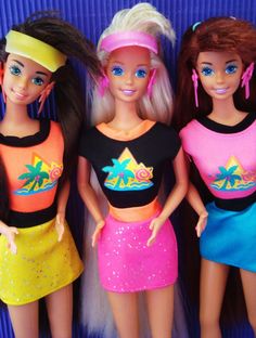 three barbie dolls standing next to each other in front of a purple background with palm trees