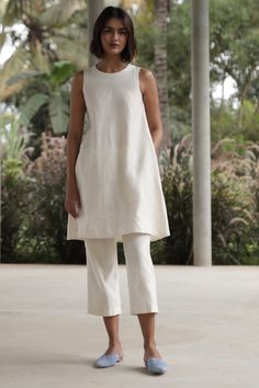 An elegant co-ord set in Lush Handwoven Chanderi silk. Sleeveless tunic with a close round neck. Back button fastening. In-seam pockets. Fully lined. Can be worn separately as a dress. Paired with easy, crop pants. Elasticated waist. In-seam pockets. Fully lined. Tip: Wear them together or mix and match with other styles in your wardrobe. Garment Measurements in inches: TUNIC XS S M L XL CHEST 34 35.5 37 38.5 40 WAIST 41 42.5 44 45.5 47 HIP 49 50.5 52 53.5 55 LENGTH 37 37.25 37.5 37.75 38 SHOULD Co Ords Outfits, Casual Indian Fashion, Coord Set, Pakistani Dress, Shirts Design, Stylish Dress Designs, Sleeveless Tunic, Suit Designs, Kurta Designs