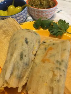 two burritos sitting on top of a wooden cutting board next to a bowl of olives