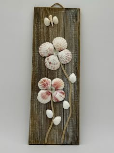 a wooden plaque with seashells and flowers on it