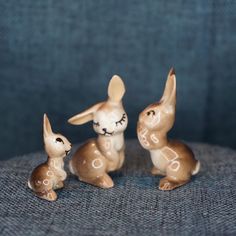 three small ceramic rabbits sitting on a couch