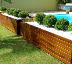 a wooden planter filled with lots of plants next to a swimming pool in a backyard