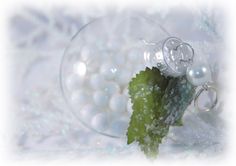 a close up of a glass ornament with pearls and a green leaf