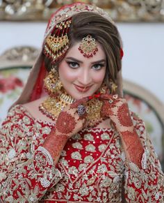 a woman in a red and gold bridal outfit holding her hands to her face