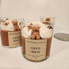 three cups filled with coffee and marshmallows on top of a white table