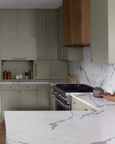 a kitchen with green cabinets and marble counter tops