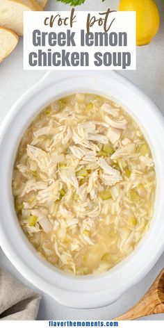 a white bowl filled with chicken soup next to sliced bread and lemons on the side