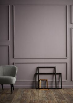 an empty room with two chairs and a table on the floor in front of a gray wall