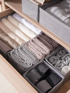 an organized drawer with folded clothes and linens in the bottom section, on a wooden table