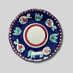 a blue and red plate with fish on it's rim, in the shape of a circle