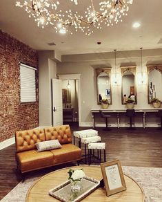 a living room filled with furniture and a chandelier hanging from the ceiling over a wooden coffee table