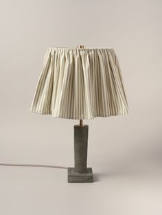 a lamp that is sitting on top of a wooden base with a white and black striped lampshade