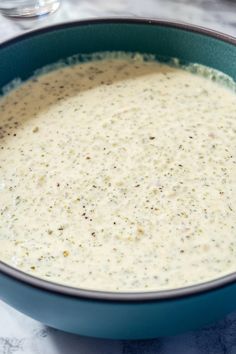 a blue bowl filled with white sauce on top of a table