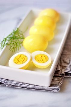 there are eggs and lemons in the white dish on the table with a sprig of dill