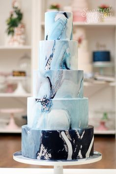 a three tiered cake with blue and white marbled icing on it's sides