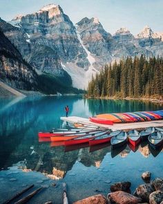 canoes are lined up on the shore of a mountain lake