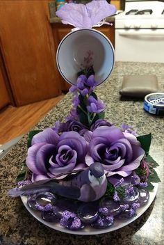 purple flowers are arranged on a plate in the middle of a kitchen counter with an empty cup