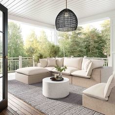 an outdoor living room with white furniture and wood flooring