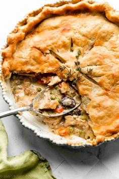 a chicken pot pie with a serving spoon in it and a piece missing from the pie