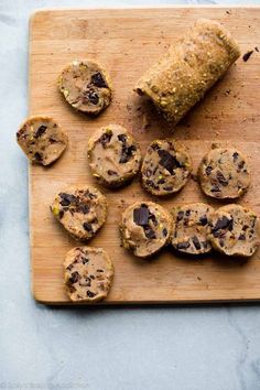 a wooden cutting board topped with cookies on top of a table