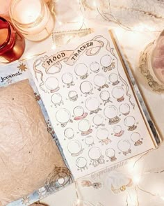 an open book sitting on top of a table next to candles and other things around it