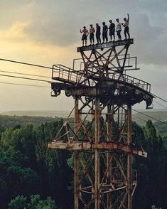 some people are standing on top of a tall structure in the middle of a forest