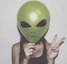 a woman with an alien mask on holding her hand up in front of her face