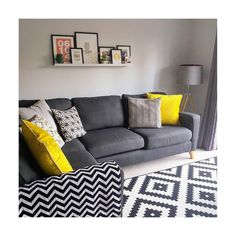 a grey couch with yellow pillows and pictures on the wall above it in a living room