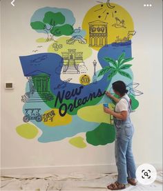 a woman standing in front of a mural with the words new orleans painted on it