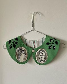 a green bib hanging on a white wall with two images of women in the middle