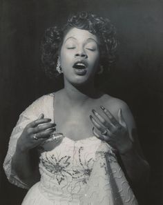 a black and white photo of a woman in a dress with her hands on her chest