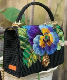 a handbag with flowers painted on it is sitting on a flower pot in front of a wooden fence