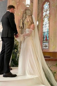 a bride and groom standing in front of a stained glass window at their wedding ceremony