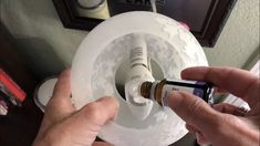 a person holding an essential oil bottle in front of a white toilet paper roller with the lid open