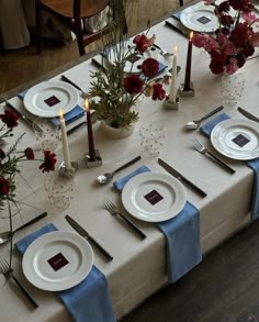 the table is set with plates and silverware, candles, and flowers in vases