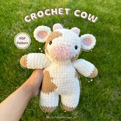 a crochet cow is shown in the grass with its hand holding it up