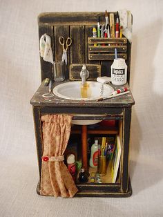 a dollhouse sink and cabinet with craft supplies