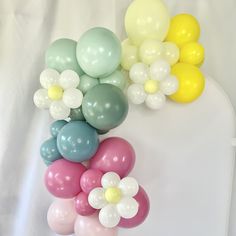 a bunch of balloons that are on top of a white table with one balloon in the air