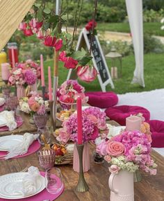 the table is set with pink and white flowers in vases, plates and napkins