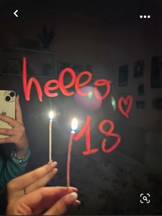 a woman taking a selfie with her cell phone and some candles in front of her