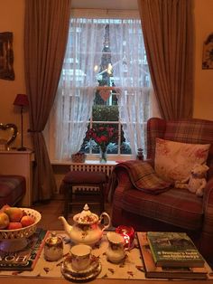 a living room filled with furniture and a christmas tree in the window sill behind it