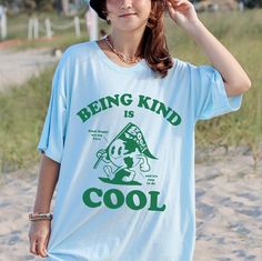 Being Kind Is Cool Shirt - Be a cool and kind human in this trendy, retro style, unisex, comfort colors shirt. SIZING Please size up for the over-sized look, refer to the size chart in the final image for the perfect fit. MATERIALS Comfort Colors are the ultimate when it comes to soft and comfortable Tshirts. They are made from 100% ring-spun cotton. The soft-washed, garment-dyed fabric brings extra coziness to your wardrobe while the relaxed fit makes it an excellent daily choice. They are high Retro Blue T-shirt With Cartoon Print, Cool Letter Print T-shirt For Spring, Trendy Relaxed Fit T-shirt With Cartoon Print, Casual Cartoon Print T-shirt With Relaxed Fit, Casual Relaxed Fit T-shirt With Cartoon Print, Cool Screen Print Tops For Spring, Cool Spring Tops With Screen Print, Trendy Crew Neck Shirt With Cartoon Print, Cool Cotton Graphic Print Top