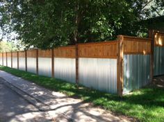 a wooden fence next to a road and trees