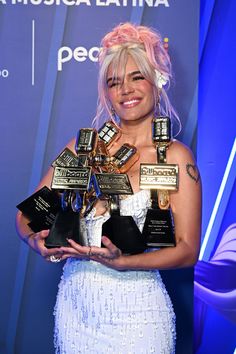 the woman is holding several awards in her hands