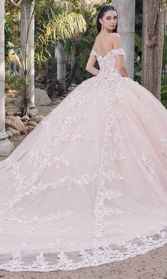 a woman in a pink wedding dress standing on the ground with her back to the camera