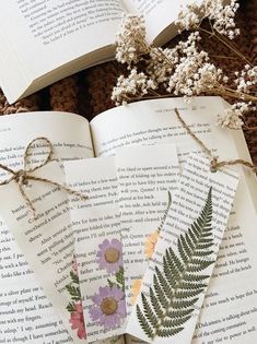 three bookmarks with flowers on them are tied to the pages of an open book